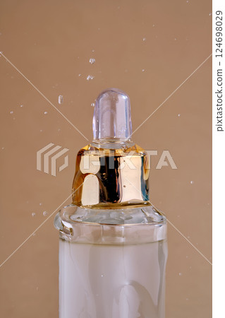 A bottle of cosmetic product with a pouring texture on top. A bottle of cosmetic product with a pouring texture on top. 124698029