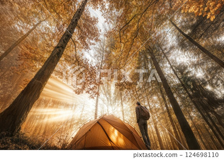 Orange tent in misty autumn forest with fallen leaves 124698110