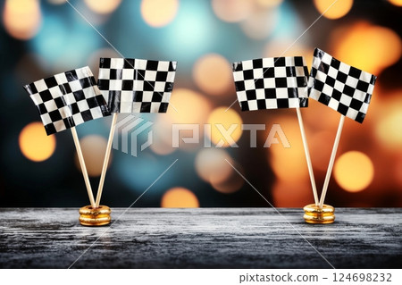 Miniature checkered flags arranged on a wooden surface with a blurred colorful background for a racing theme celebration 124698232