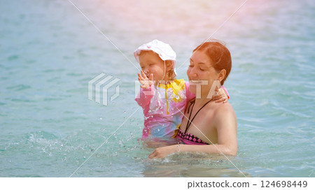 Family of mother and daughter swims in ocean enjoying small waves 124698449