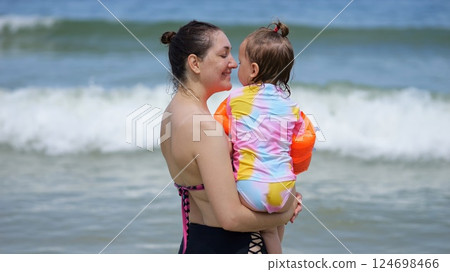 Mother holding and kissing daughter at beach Mother holding and kissing daughter at beach 124698466