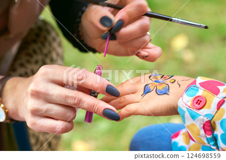 Child's hand with artist draws a colorful paint 124698559