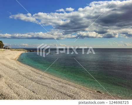 Pebble beach and blue sea with white clouds. 124698725