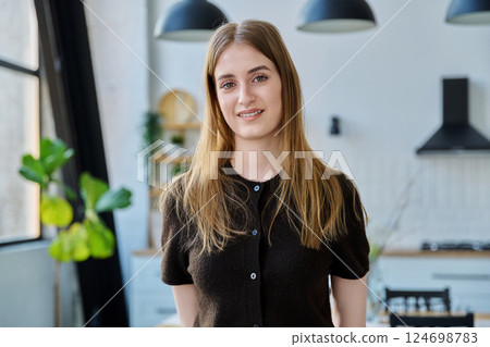 Portrait of beautiful young girl looking at camera, home interior background 124698783