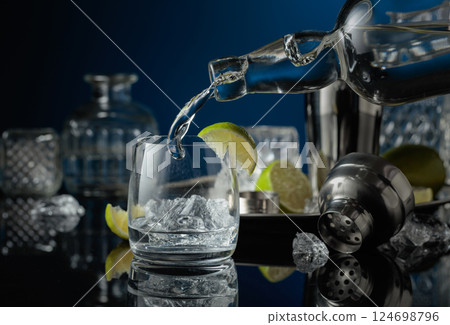 Vodka is poured into a glass with ice. 124698796