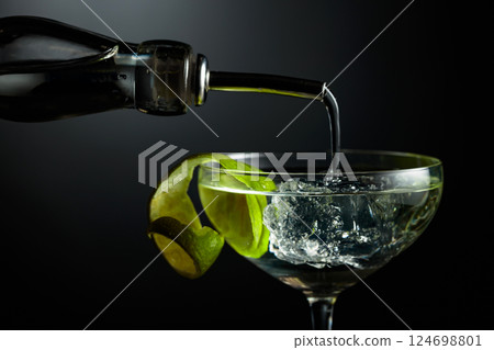 Vodka or gin is poured into a glass with ice. 124698801