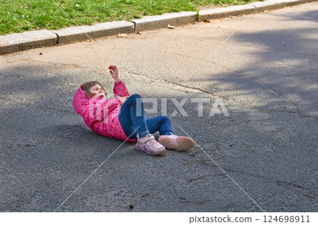 A child who fell on the asphalt and hit his hand is crying in pain 124698911