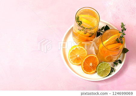 Detox drink with lemon, mint, lime and orange on a light table, mojito or cocktail improves metabolism, promotes weight loss and strengthens immunity, healthy lifestyle concept, selective focus. 124699069