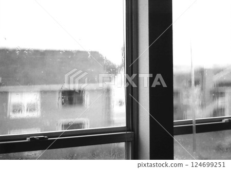 雨天裡，窗玻璃上滴落著雨滴，水流淌，建築物朦朧，遠處是陰雲密布的天空 — — 黑色和白色 124699251