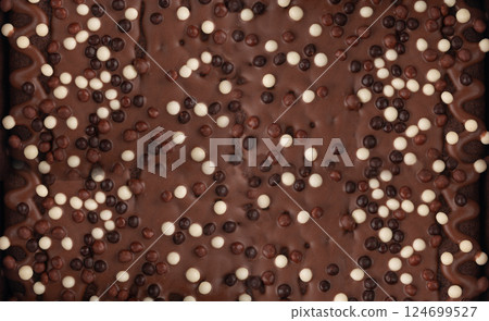 Chocolate brownie cake texture background sprinkled with white and dark balls, brounie banner 124699527