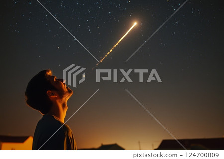 A person gazes upward in amazement as a brilliant meteor blazes across the starry night sky, its golden trail reflected in their wide-eyed expression 124700009