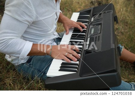 Musician Boy Plays The Keyboard Sitting In The Meadow In Calabria Countryside 124701038