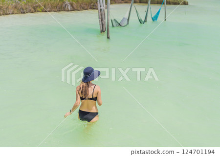 Woman enjoying the crystal-clear turquoise waters of a lagoon in Mexico. Tropical relaxation and paradise escape concept Woman enjoying the crystal-clear turquoise waters of a lagoon in Mexico. Tropical relaxation and paradise escape concept 124701194