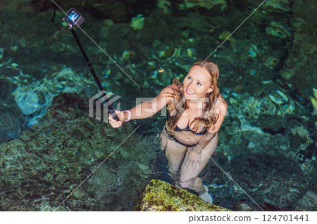 Female tourist enjoying a refreshing swim in a Mexican cenote with turquoise water. Adventure, travel, and nature exploration concept 124701441