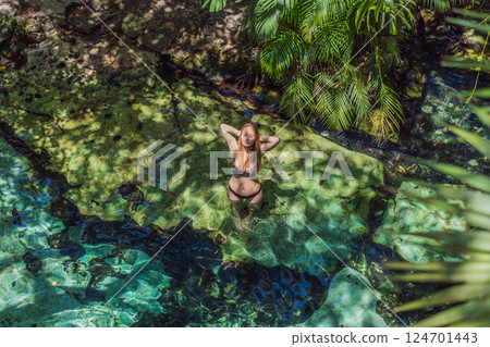 Female tourist enjoying a refreshing swim in a Mexican cenote with turquoise water. Adventure, travel, and nature exploration concept Female tourist enjoying a refreshing swim in a Mexican cenote with turquoise water. Adventure, travel, and nature exploration concept 124701443