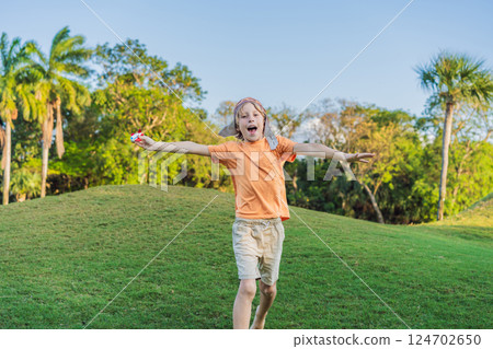 Boy wearing a pilot hat running through the grass with a toy airplane, dreaming of adventures. Childhood, imagination, and freedom concept Boy wearing a pilot hat running through the grass with a toy airplane, dreaming of adventures. Childhood, imagination, and freedom concept 124702650