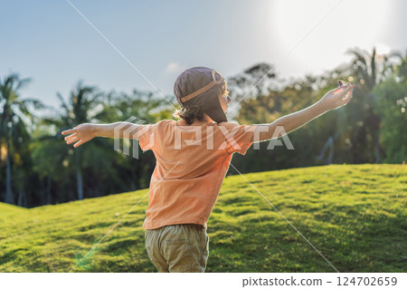 Boy wearing a pilot hat running through the grass with a toy airplane, dreaming of adventures. Childhood, imagination, and freedom concept Boy wearing a pilot hat running through the grass with a toy airplane, dreaming of adventures. Childhood, imagination, and freedom concept 124702659