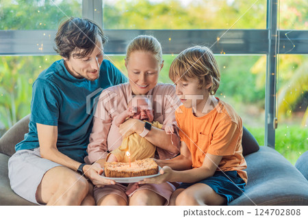 Happy family celebrating their newborn first month with a cake. Parents, teenage son, and one-month-old baby sharing a joyful milestone moment together. Family love and bonding concept 124702808