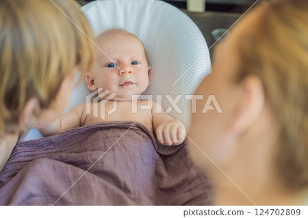 Mother and older son admiring their newborn baby in a cozy infant nest. Family bonding and sibling love concept Mother and older son admiring their newborn baby in a cozy infant nest. Family bonding and sibling love concept 124702809