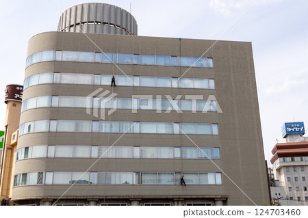 Cleaning worker cleaning the windows of a building Stock photo of working at height 124703460