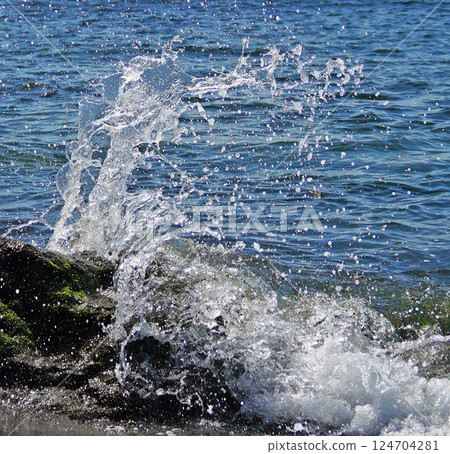 Waves crashing onto rocks on a sandy beach 124704281