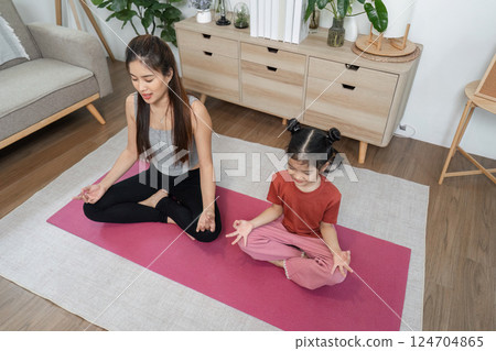 Joyful Yoga and Mindfulness. Relaxed mother and daughter practicing yoga together, enjoying a shared moment. Joyful Yoga and Mindfulness. Relaxed mother and daughter practicing yoga together, enjoying a shared moment. 124704865