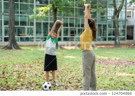 Warm-up and Playfulness. A woman and a young boy stretching and enjoying their time in the park. Warm-up and Playfulness. A woman and a young boy stretching and enjoying their time in the park. 124704866