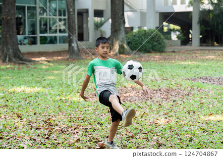 Skill Development and Outdoor Fun. A boy practicing soccer skills with a woman in a park setting. Skill Development and Outdoor Fun. A boy practicing soccer skills with a woman in a park setting. 124704867