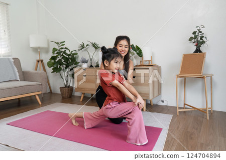 Fitness and Playtime. A fun yoga session where a mother guides her daughter through playful stretching exercises. 124704894