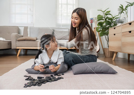 Family Fun and Playtime. A joyful mother and daughter enjoy a playful moment while engaging with dominoes. 124704895