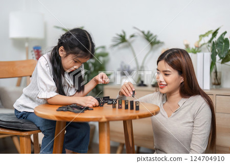 Playful Learning and Family Connection. A mother and daughter deepen their bond over a game of dominoes. 124704910