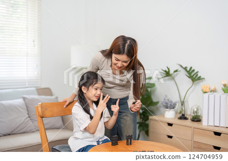 Interactive Playtime and Education. A dedicated mother teaches her child through a game in their comfortable living space. Interactive Playtime and Education. A dedicated mother teaches her child through a game in their comfortable living space. 124704959