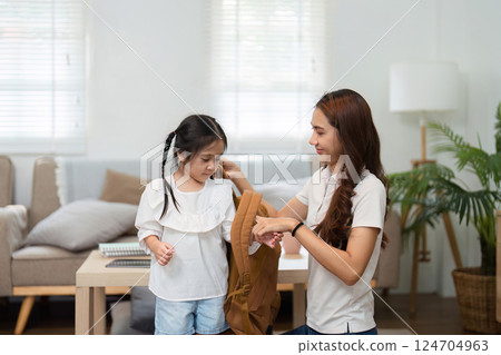 Encouraging Confidence in the School Journey. A mother helps her daughter dress while preparing for school. Encouraging Confidence in the School Journey. A mother helps her daughter dress while preparing for school. 124704963