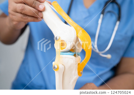 Asian doctor holding spinal nerve and bone model, Lumbar spine displaced herniated disc fragment for treatment medical in the orthopedic department. 124705024