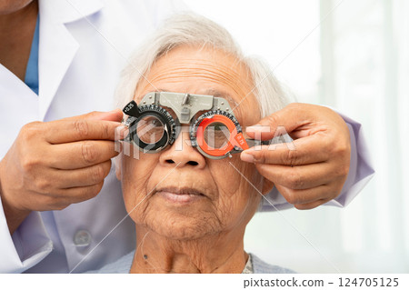 Asian senior woman wearing ophthalmic vision eye test and using optical trial frame. 124705125