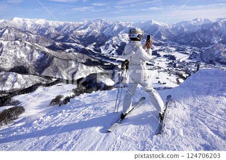 在滑雪勝地的山頂，一名女子正在拍攝下方的美景 124706203