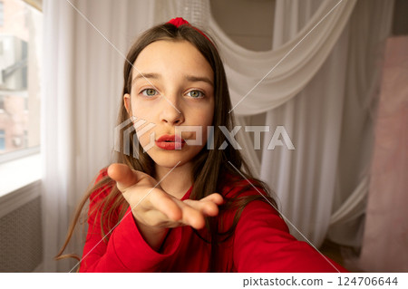 Teen girl blowing kiss toward camera in selfie photo. Teen girl blowing kiss toward camera in selfie photo. 124706644