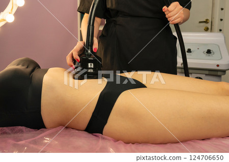 Beautician performs non-invasive abdominal contouring with cavitation. Beautician performs non-invasive abdominal contouring with cavitation. 124706650