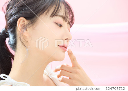 A refreshing beauty image of a young woman photographed against a pink background 124707712