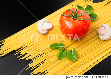 Fresh tomato, mushrooms, and spinach leaves on spaghetti, placed on a black table composition of pasta ingredients Fresh tomato, mushrooms, and spinach leaves on spaghetti, placed on a black table composition of pasta ingredients 124709441
