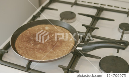 Prepare a delicious pancake using a frying pan placed on a gas stove, ideal for breakfast or lunch 124709975