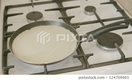 Cooking delicious crepes on a gas stove using a nonstick frying pan requires skill and practice 124709983