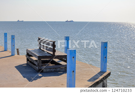 An old wooden bench on jetty, Rest area at the fish pier. An old wooden bench on jetty, Rest area at the fish pier. 124710233