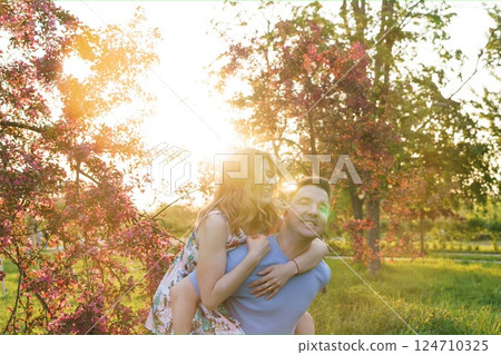 A happy couple embrace a blooming orchard at sunset A happy couple embrace a blooming orchard at sunset 124710325