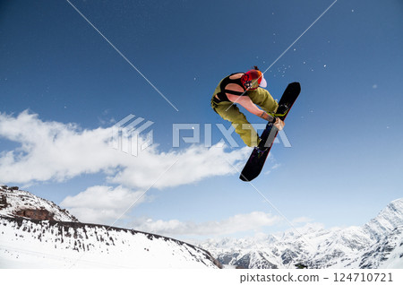 Beginner snowboarder riding on sunny day, performing trick in air. Sport tourist snapshot while snowboarding during winter vacation 124710721