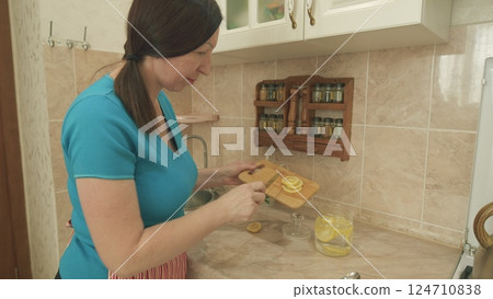 A Woman is Preparing Refreshing Healthy Lemon Slices in a Stylish Modern Kitchen Space 124710838