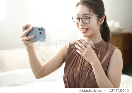 Young woman sitting in bed and looking at her smartphone Young woman sitting in bed and looking at her smartphone 124710943