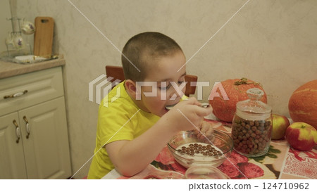 A playful child happily enjoys a delicious breakfast in a cozy kitchen at the table A playful child happily enjoys a delicious breakfast in a cozy kitchen at the table 124710962