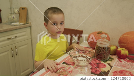 A small child happily eating a nutritious breakfast while sitting in a cozy kitchen setting A small child happily eating a nutritious breakfast while sitting in a cozy kitchen setting 124710963