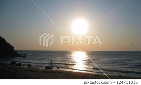 Sunset over the sea and sandy beach 124711010